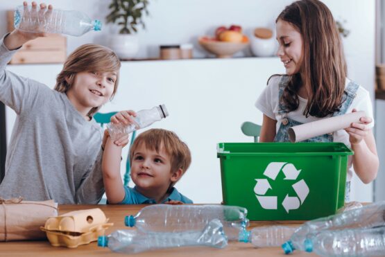 Lächelnde Kinder trennende Plastikflaschen