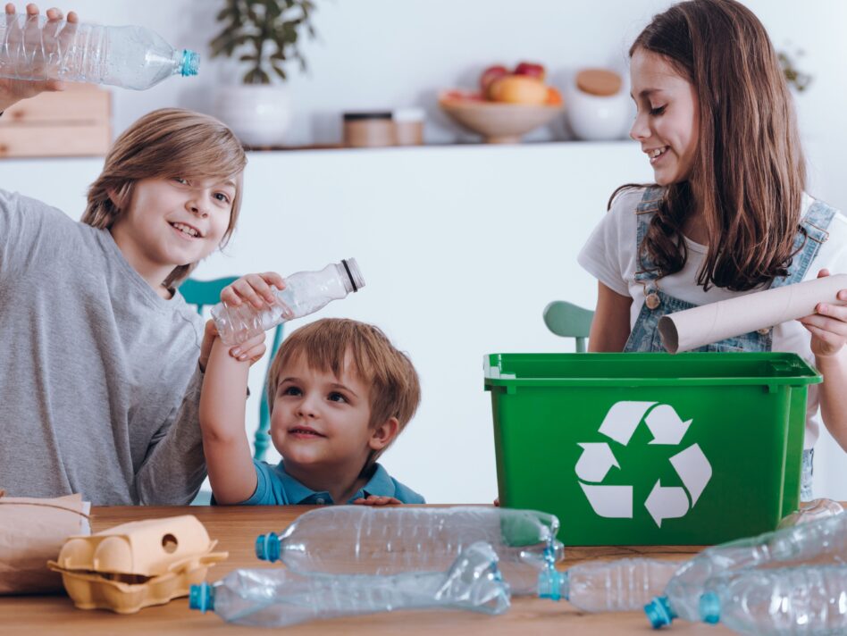 Lächelnde Kinder trennende Plastikflaschen