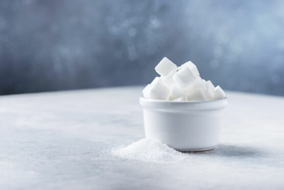 Sugar cubes and grain of sugar on tje light background, selective focus