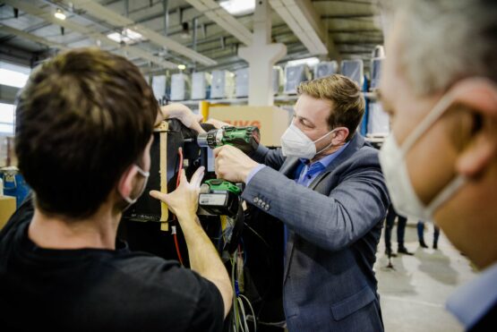 Landesrat Stefan Kaineder mit Akkuschrauber bei Firma Guntamatic