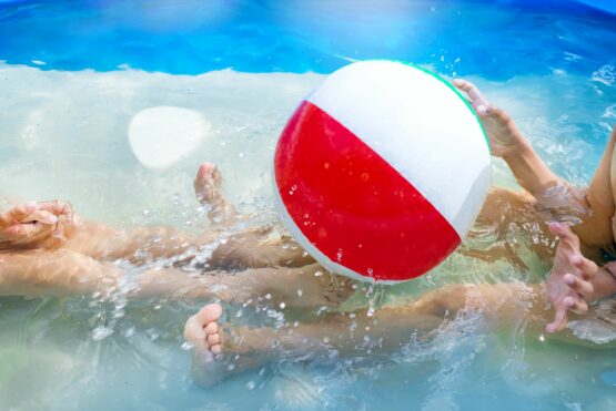 Kids playing at outdoor swimming pool. Little girl and boy play and swim in a home inflated pool .Water toys for children. Concept for summer vacations, relaxation and fun in the sunshine