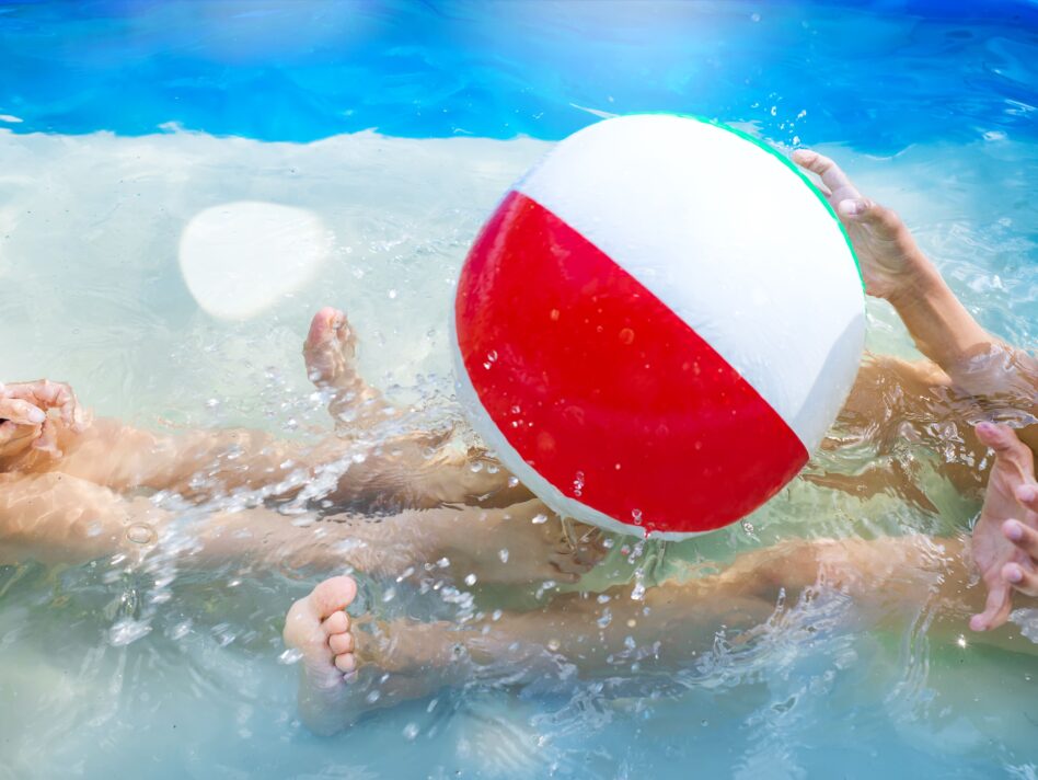 Kids playing at outdoor swimming pool. Little girl and boy play and swim in a home inflated pool .Water toys for children. Concept for summer vacations, relaxation and fun in the sunshine