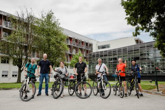 Markus Lang (passathon), Oliver Zörrer (Verwalter Eisenbahnerheim), Christine Gruber (Grüne Bad Schallerbach), Klima-Landesrat Stefan Kaineder, Bürgermeister Markus Brandlmayr (Bad Schallerbach), Günter Lang (passathon) und Maximilian Lang (passathon) vor der mustersanierten Gesundheitseinrichtung der Versicherungsanstalt für Eisenbahn und Bergbau in Bad Schallerbach