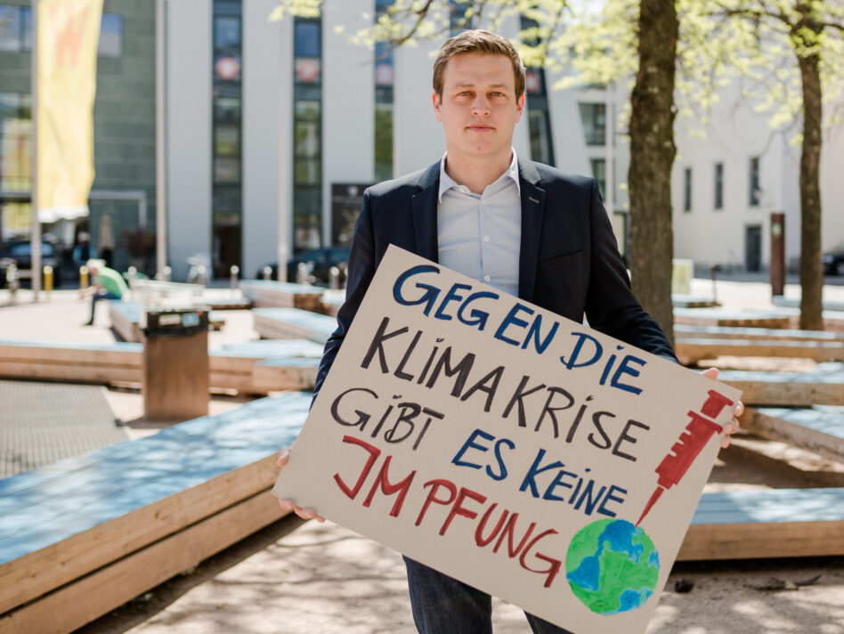 Stefan Kaineder mit Schild "Gegen die Klimakrise gibt es keine Impfung"