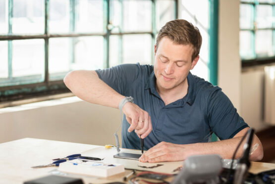 Landesrat Stefan Kaineder legt selbst Hand an und repariert ein Handy