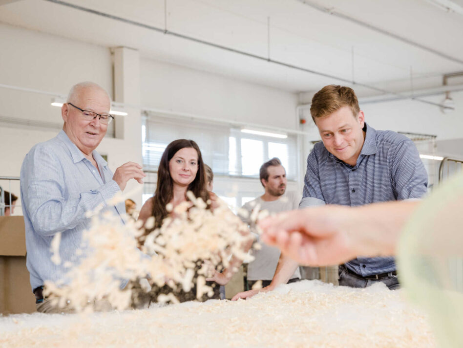 Betten Reiter Geschäftsführer Peter Hildebrand, Veronika Bohrn Mena (Initiative Lieferkettengesetz) und Umwelt- und Klima-Landesrat Stefan Kaineder bei der Produktion einer Zirbendecke in der Manufaktur von Betten Reiter in Leonding