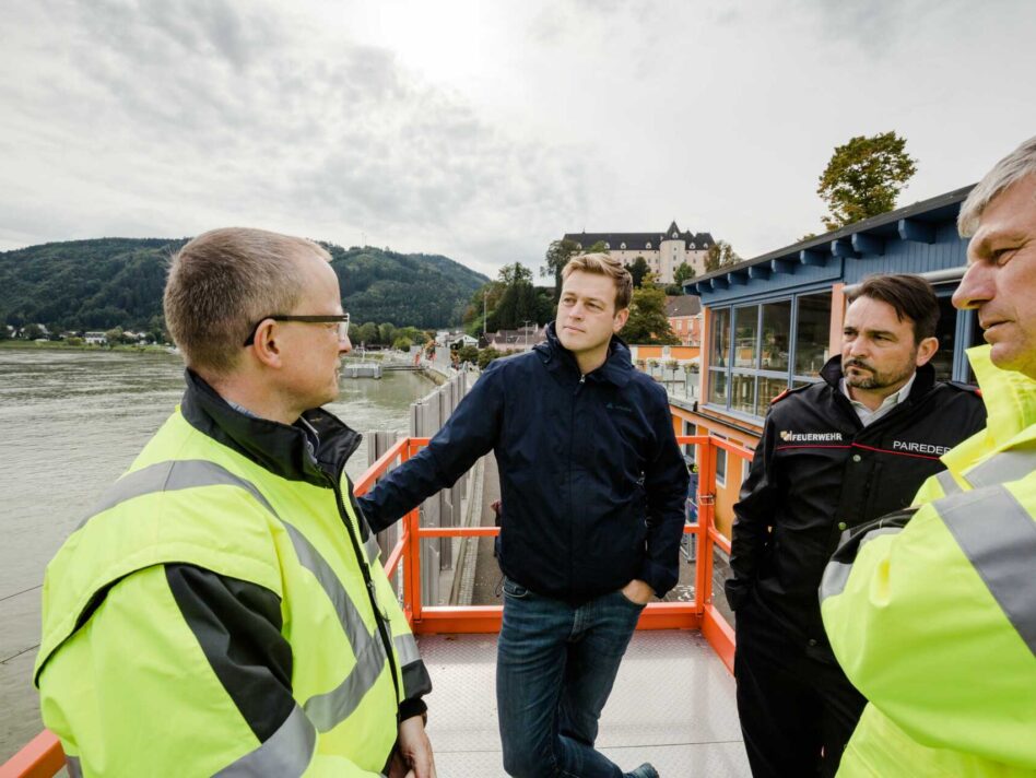 Der behördliche Einsatzleiter Bezirkshauptmann Werner Kreisl, Landesrat Stefan Kaineder, der technische Einsatzleiter Bezirksfeuerwehrkommandant Eduard Paireder und Machlanddamm Geschäftsführer Herbert Froschauer in Grein auf einer Hebebühne zum Aufbau des mobilen Hochwasserschutzes