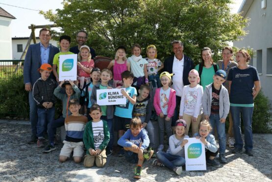 Umwelt- und Klima-Landesrat Stefan Kaineder mit den erwartungsvollen Schüler/innen der Grundstufe 1 der Volksschule Atzbach, Norbert Rainer Klimabündnis Oberösterreich, Bgm. Berthold Reiter, Klassenlehrerin Elisabeth Hörmann, Dir.in Daniela Mühlleitner und Workshopleiterin Bettina Stock kurz vor dem Start in den Klimabündnis Workshop in einem nahegelegenen Waldstück.