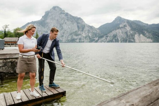 Ing.in Sabine Kapfer von der Gewässergüteaufsicht des Landes OÖ zeigt Umwelt- und Klima-Landesrat Stefan Kaineder die Probenahme zur Überprüfung der Badequalität am Traunsee.