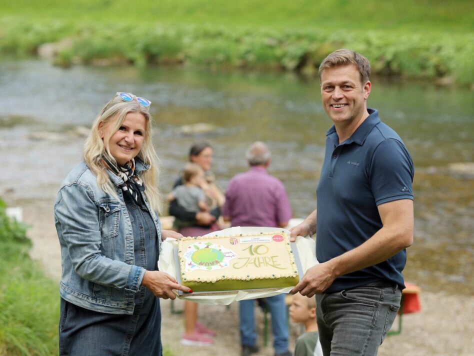 Umwelt- und Klima-Landesrat Stefan Kaineder bedankt sich mit einer Jubiläumstorte bei der Ideengeberin und Organisatorin des UMWELT:SPIEL:RAUM Christiane Weissenböck für das 10-jährige Engagement.