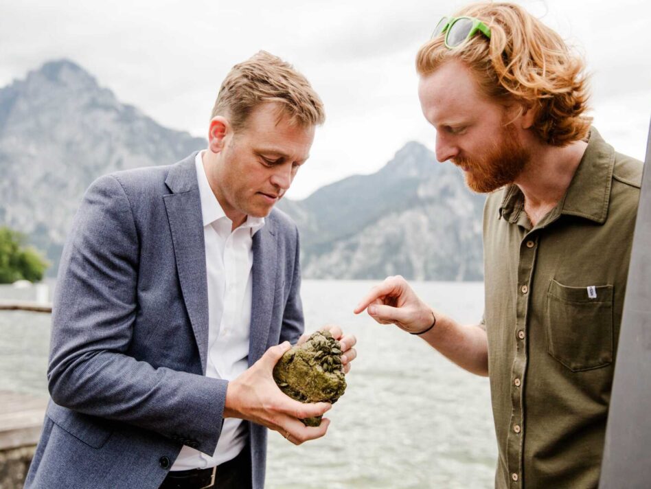Sichtbares Warnsignal aus dem Traunsee: Umwelt- und Klima-Landesrat Stefan Kaineder und Gewässerökologe Nikolaus Schobesberger vom Land OÖ mit einem Stein, der dicht von Quagga-Muscheln besiedelt ist.